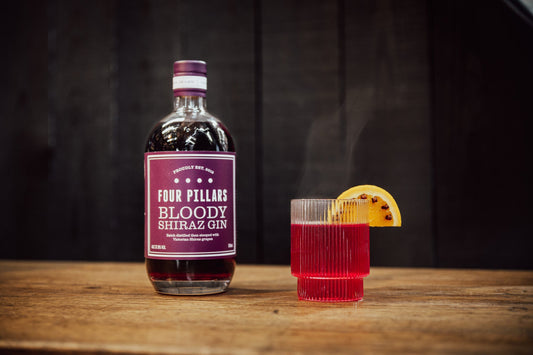 A Four Pillars Gin Bloody Shiraz Gin bottle beside a warm, Bloody Hot Negroni.