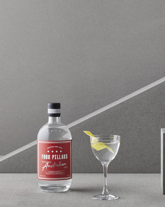 A bottle of Four Pillars Modern Australian Gin and a Martini garnished with a lemon twist.