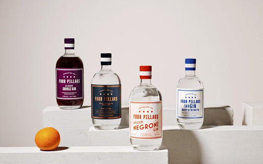 Four bottles of Four Pillars Gin next to an orange.