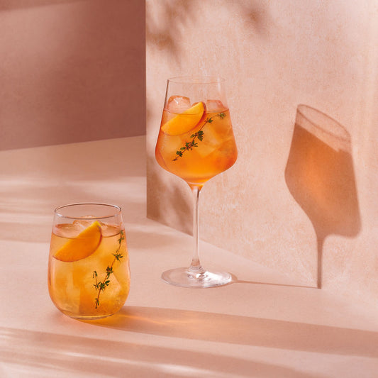 Two glasses in front of a pink wall of Four Pillars Gin x Go-To skincare gin cocktail spritz.
