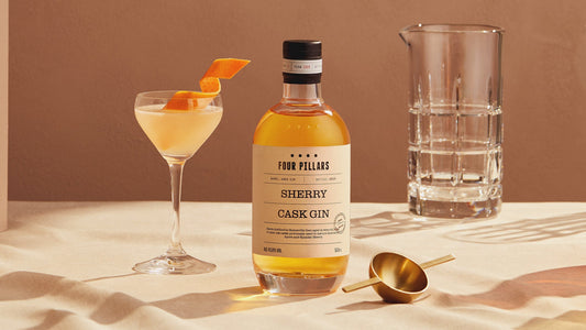 A glass of a delicious modern classic gin cocktail with a twist next to a bottle of Sherry Cask Gin.