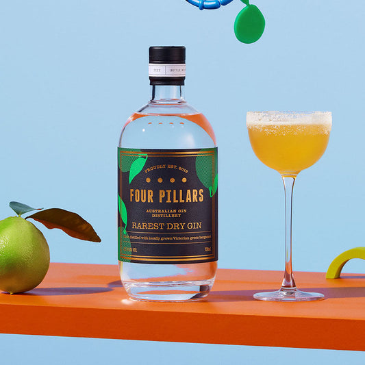 A bottle of Four Pillars Gin Rarest Dry Gin besides an earl grey and gin cocktail.
