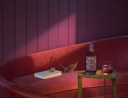 A bottle of Four Pillars Gin Bloody Underhill Shiraz in a red and purple room.