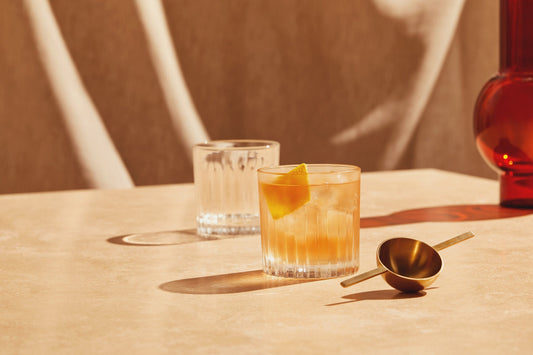 A delicious, refreshing, orange gin cocktail in a short glass garnished with an orange.