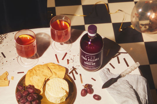 A bottle of bloody shiraz gin next to two blood g&t's and a cheese platter.