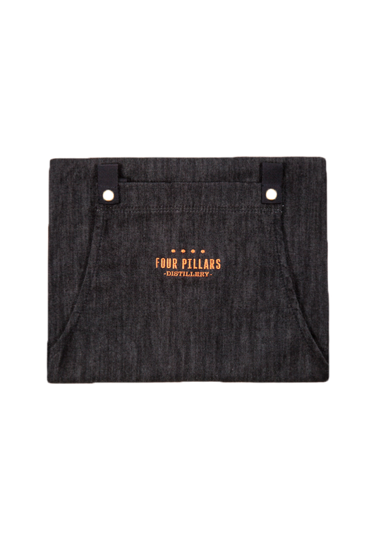 A folded Four Pillars black cotton Denim Apron with Copper Embroidery