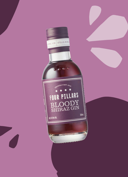 A mini bar bottle sized Four Pillars Gin Bloody Shiraz Gin floating in front of a fun purple background.