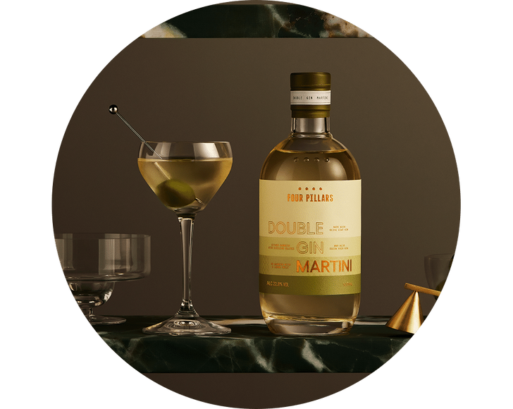 a circular framed photo of the Four Pillars Gin bottled cocktail, next to a dirty martini with an olive on a green marble shelf, sitting beside fancy barware.