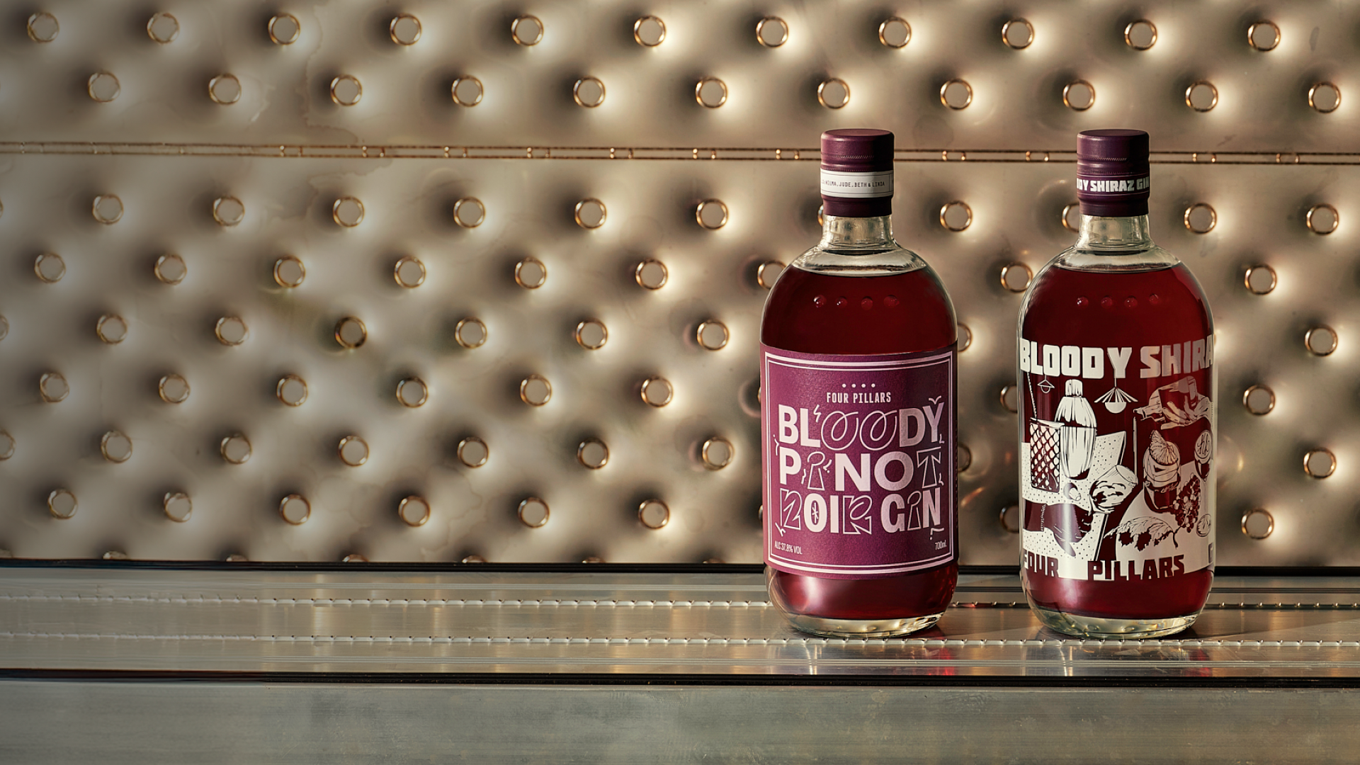 One bottle of Bloody Pinot Noir Gin next to a bottled of Bloody Shiraz Gin with the 2024 limited edition label by Kris Leombruni