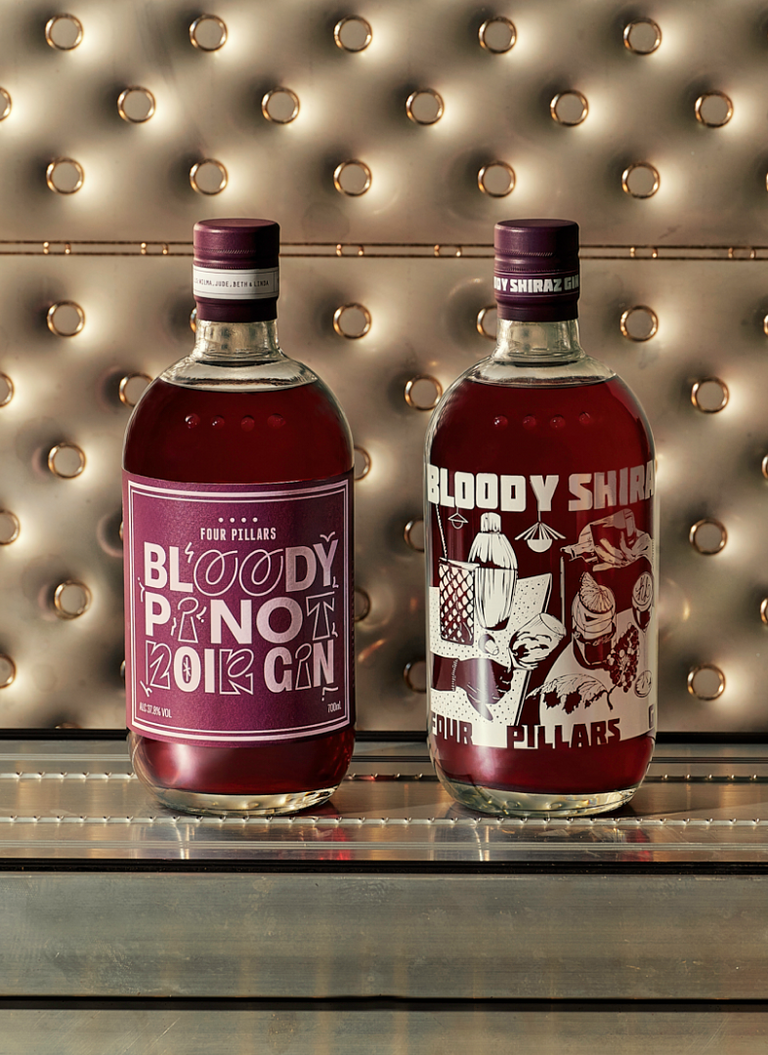A cropped photo of  Four Pillars Gin's Bloody Pinot Noir Gin next to a bottled of Bloody Shiraz Gin with the 2024 limited edition label by Kris Leombruni