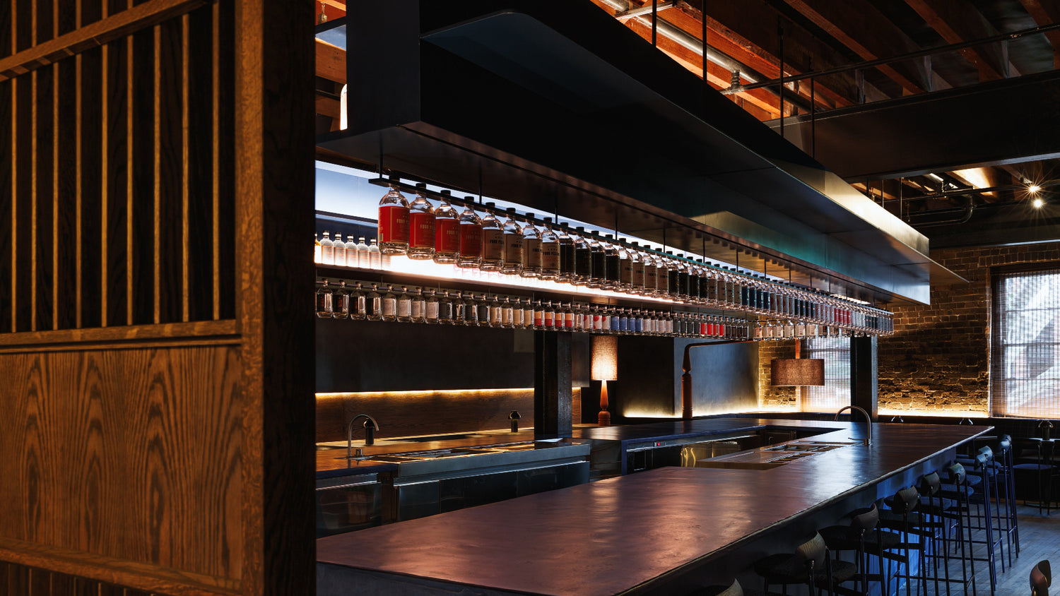 Eileen's Bar at the Four Pillars Laboratory in Sydney. A blue bar with a wooden counter and shelves displaying gin bottles in a dimly lit setting.