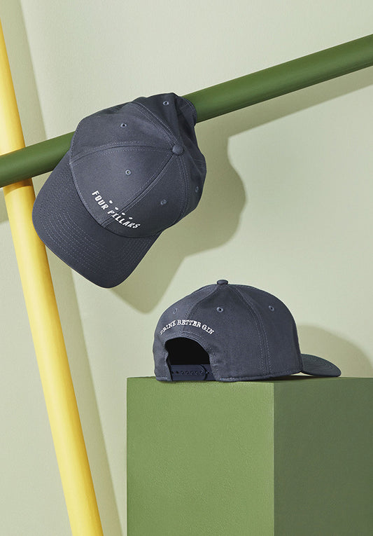 A Four Pillars gin cap rests on a stool, set against a vibrant green background.