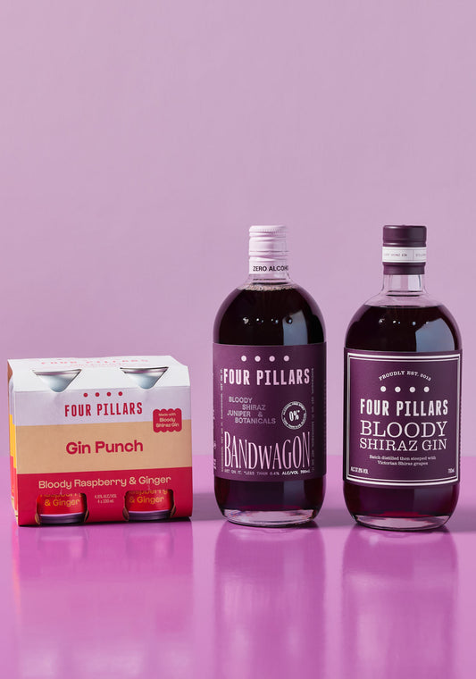 Four Pillars Bloody range featuring a 4-pack of Gin Punch cans, a bottle of Bandwagon Bloody (alcohol-free), and a bottle of Bloody Shiraz Gin, set against a pink background