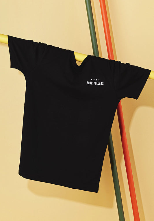 A standard black tshirt with a white embroided  Four Pillars Gin logo on the left breast, hanging on a yellow pole.