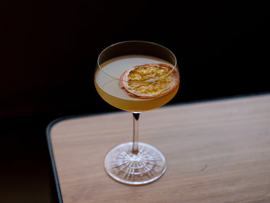 Four Pillars non-alcoholic cocktail, Breakfast Faux-tini in a glass with a lemon twist on a wooden surface.