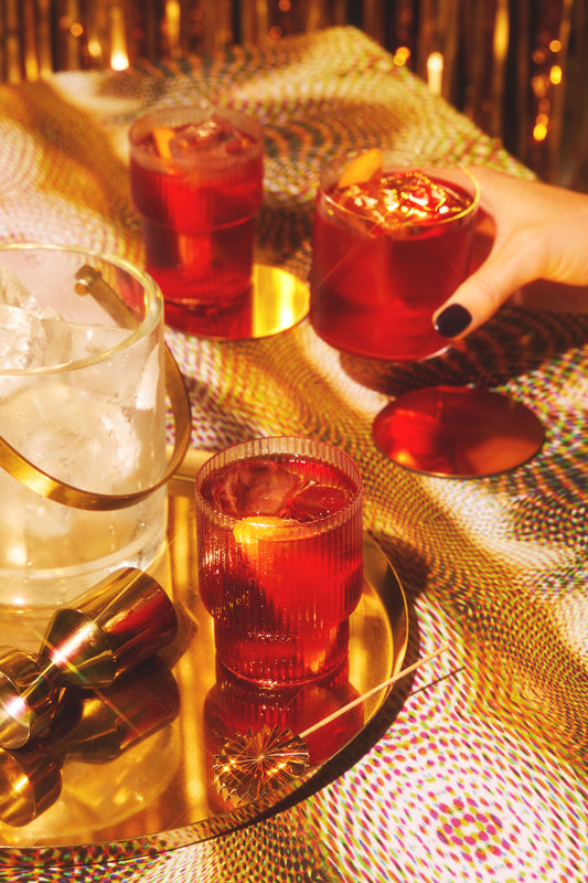 A festive display of three negroni gin cocktails on a gold tablecloth. 