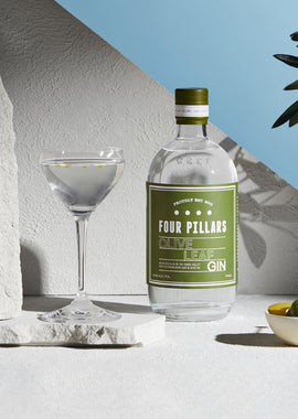 Four Pillars Olive Leaf gin bottle with a glass on a light background