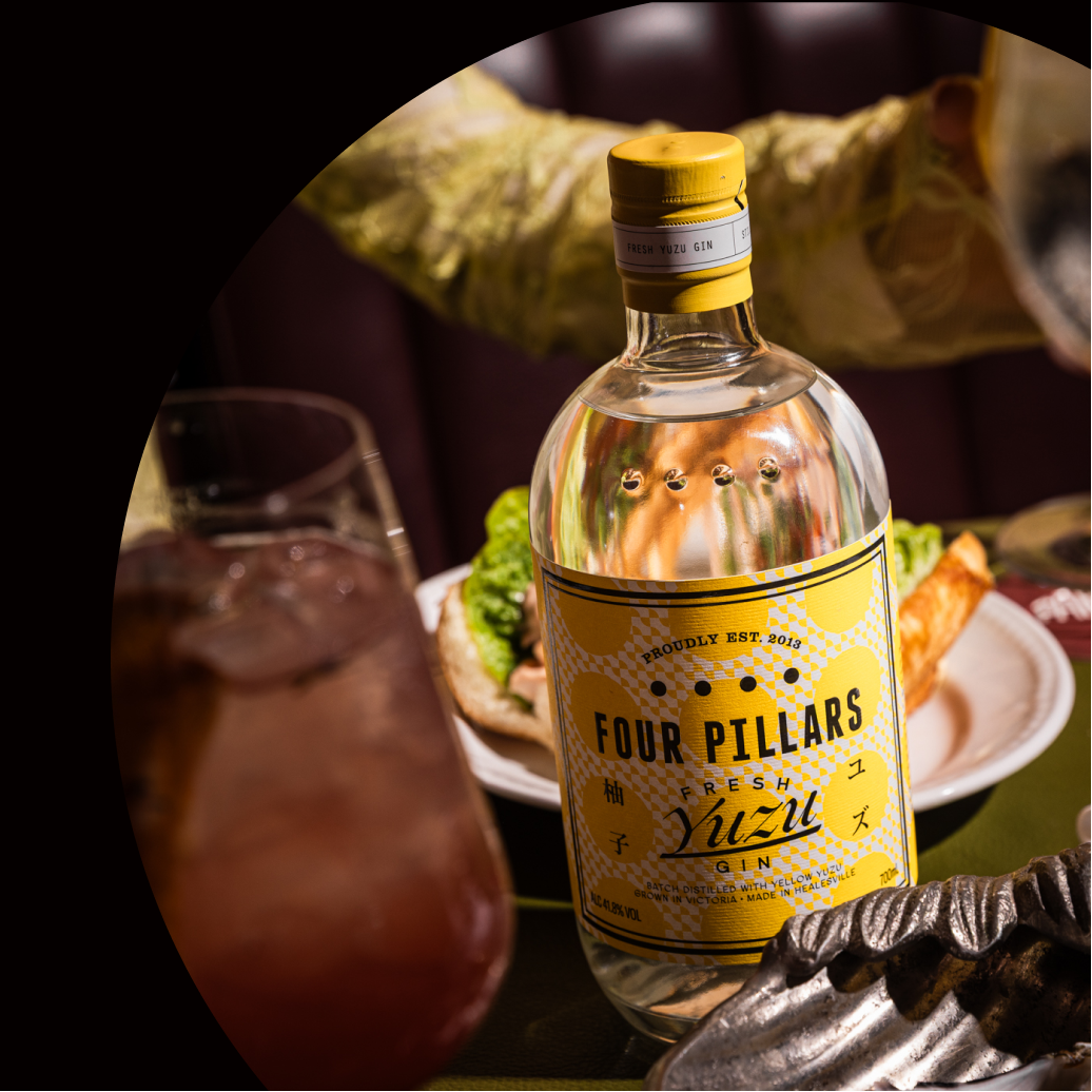 Four Pillars Yuzu Gin bottle with a glass of a spritz in a restaurant setting.