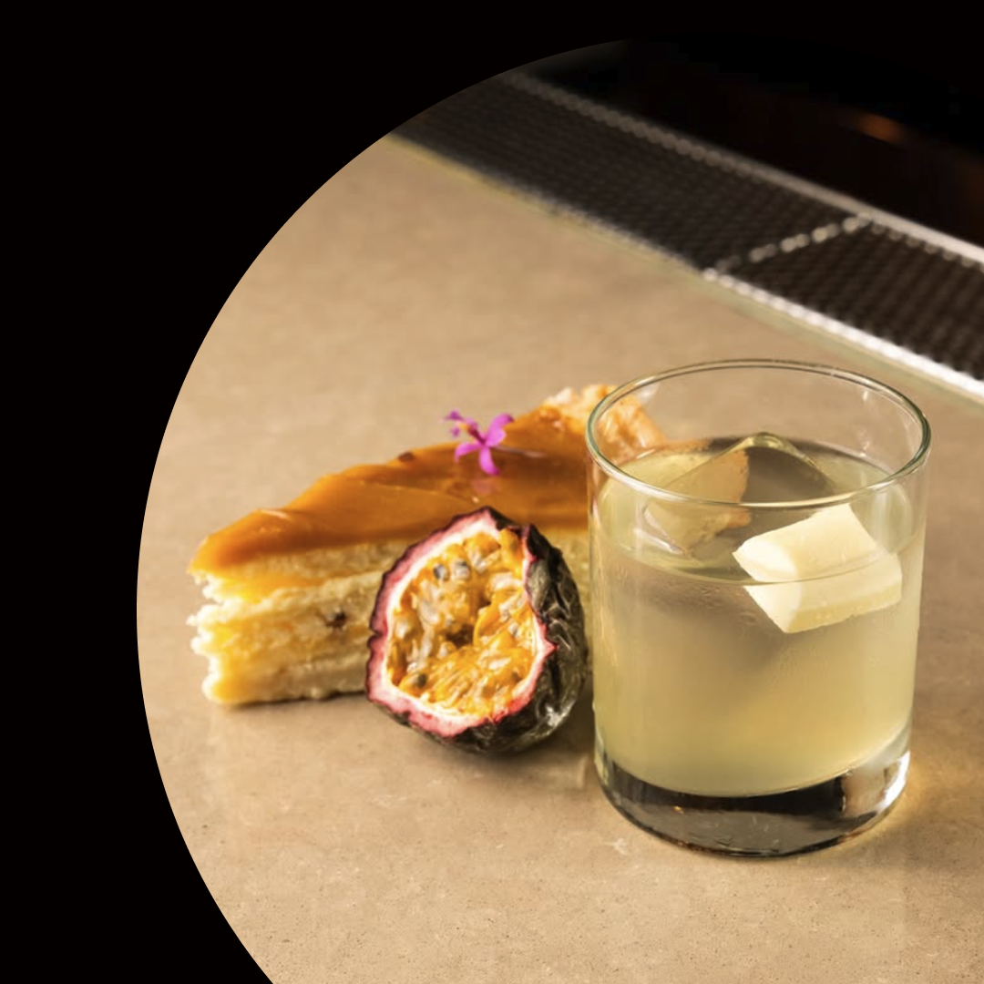 Cocktail glass with a slice of cake and a dessert on a black background with text about Wat Den Perth.