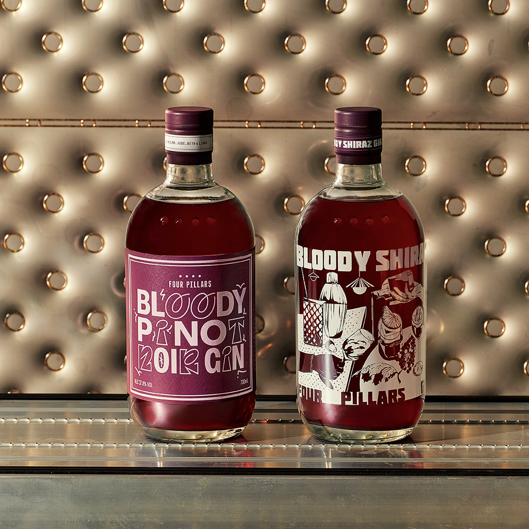 Two bottles of Four Pillars gin - Bloody Shiraz Gin & Bloody Pinot Noir Gin with limited-edition labels on a metallic surface.