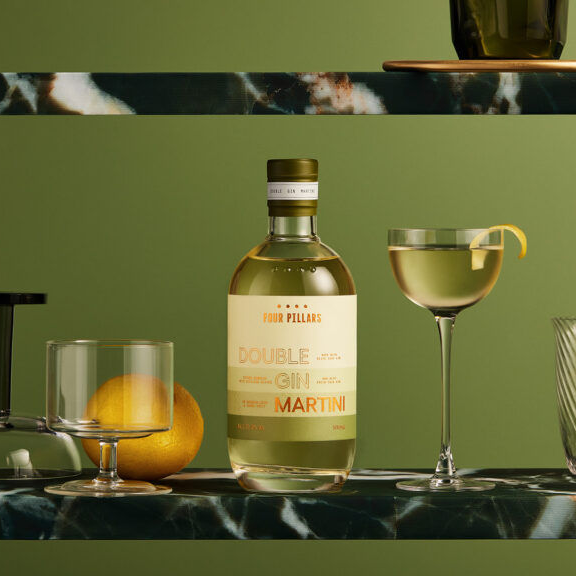 Bottle of Four Pillars Double Gin Martini with a cocktail glass and garnish on a green background
