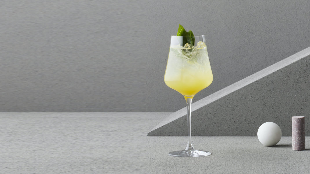 Cocktail in a glass with a lemon twist on a gray background