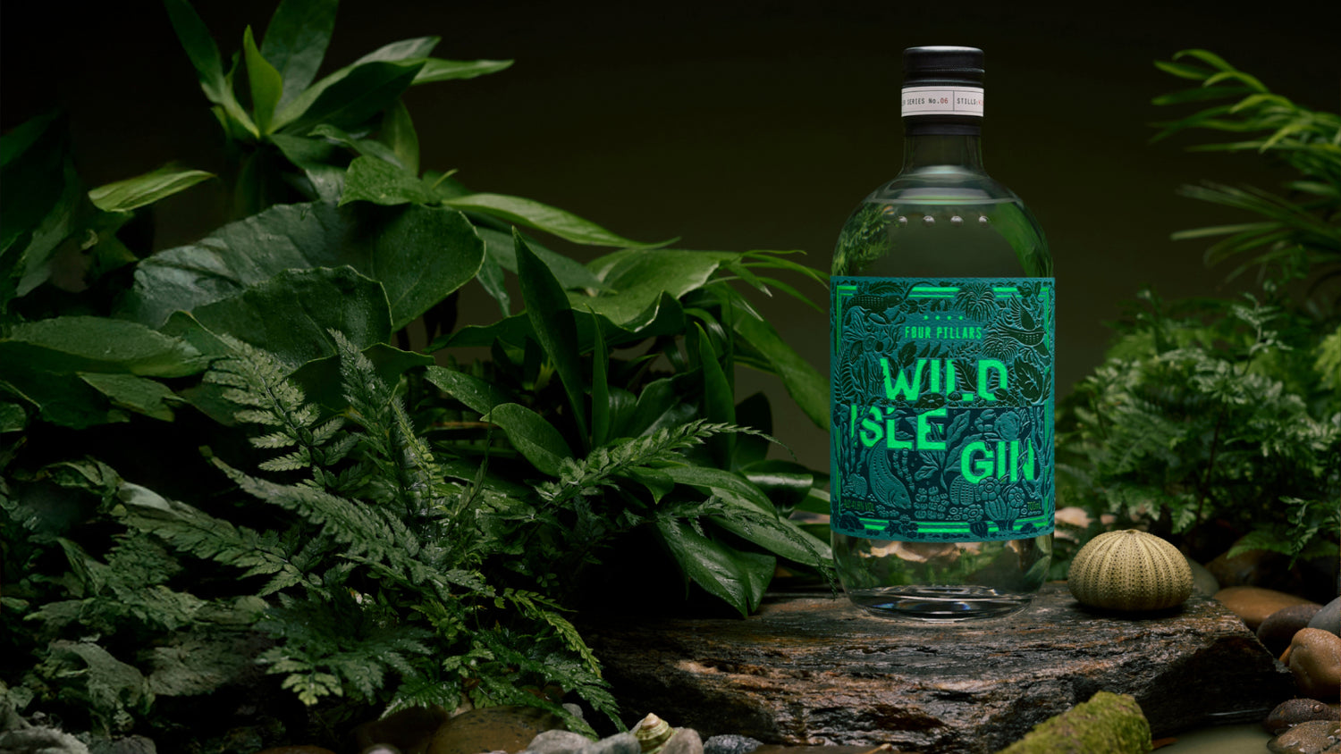 Bottle of Wild Isle Gin surrounded by greenery on a dark background.