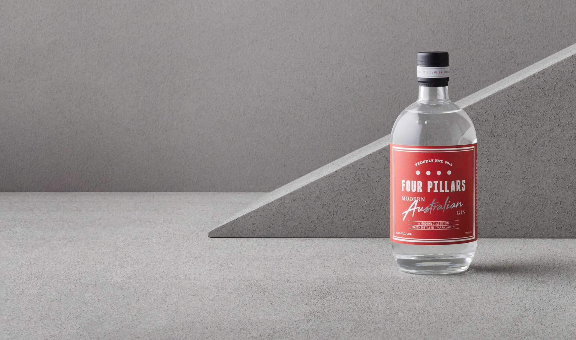 Four Pillars Gin, Modern Australian Gin with its bold red label, surrounded by grey cement. 