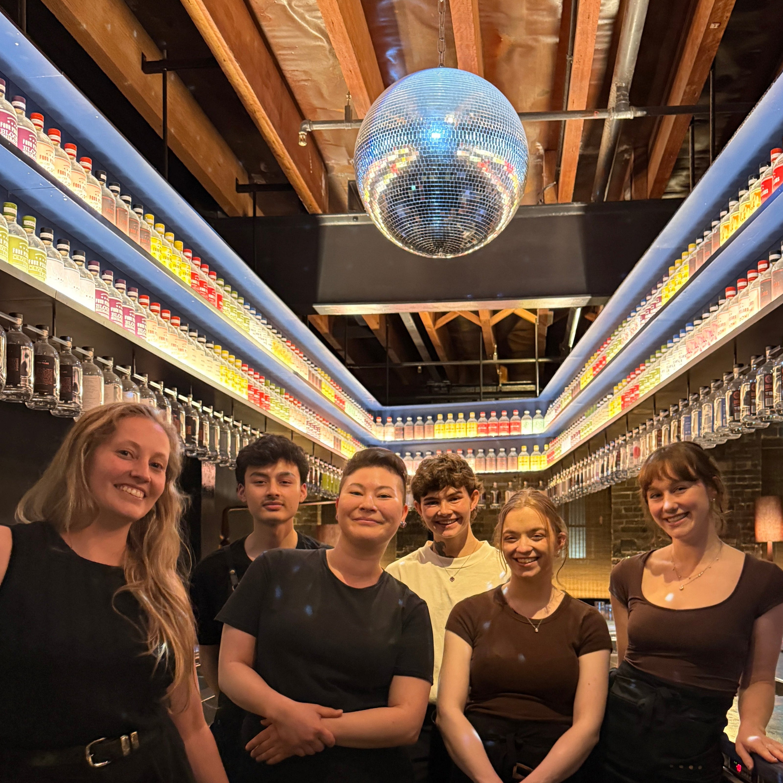 Bar team of the Four Pillars Lab pose under the disco ball in Eileen's Bar.