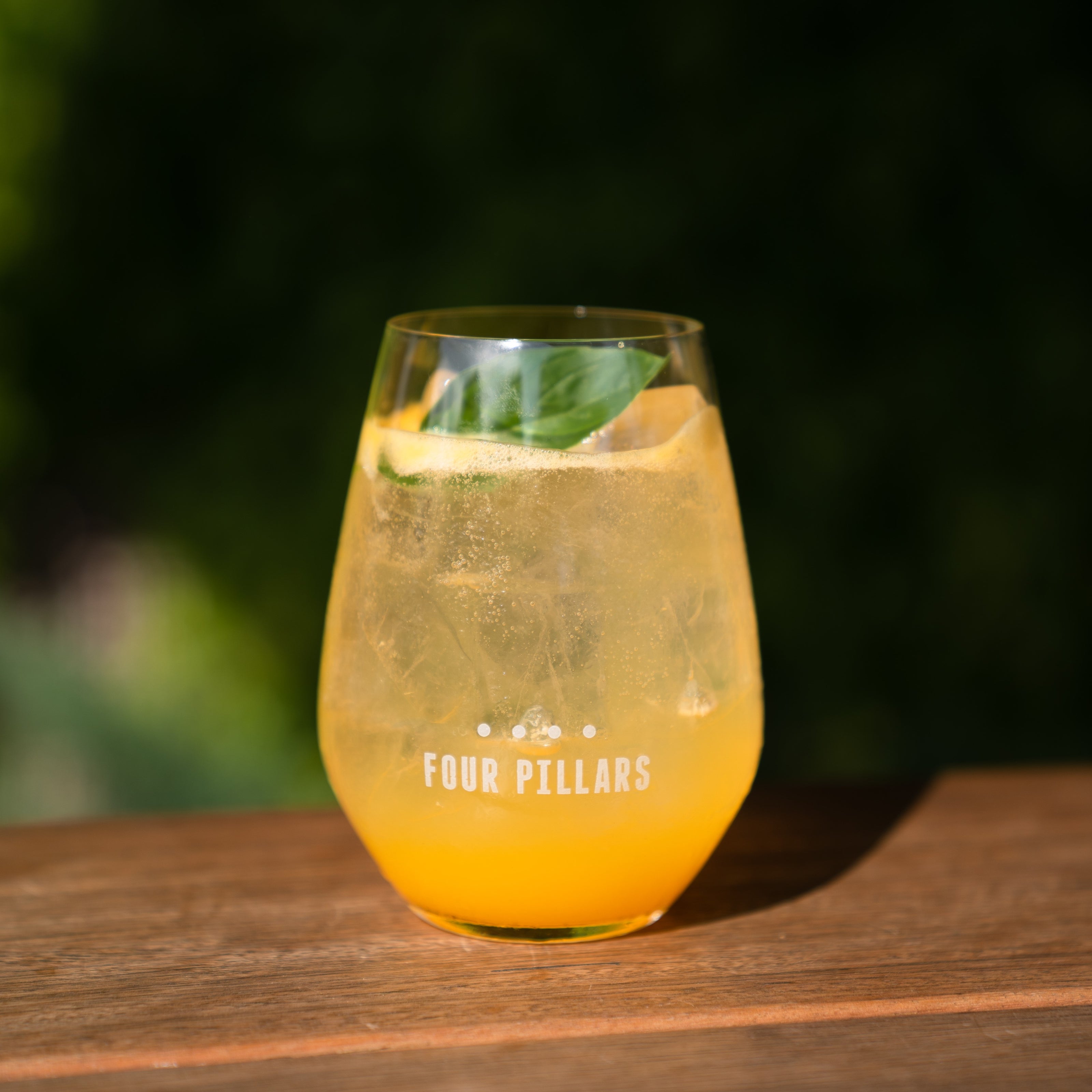 A glass containing a Gin Spritz cocktail sits on a ledge. The cocktail contains Four Pillars Modern Australian Gin, orange juice and prosecco.