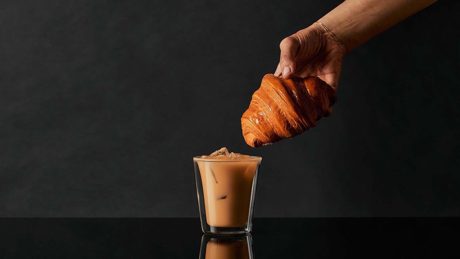 A Lune Croissanterie croissant being dipped into an Almond Latte Gin Cocktail made with Four Pillars Gin Croissant Gin. 