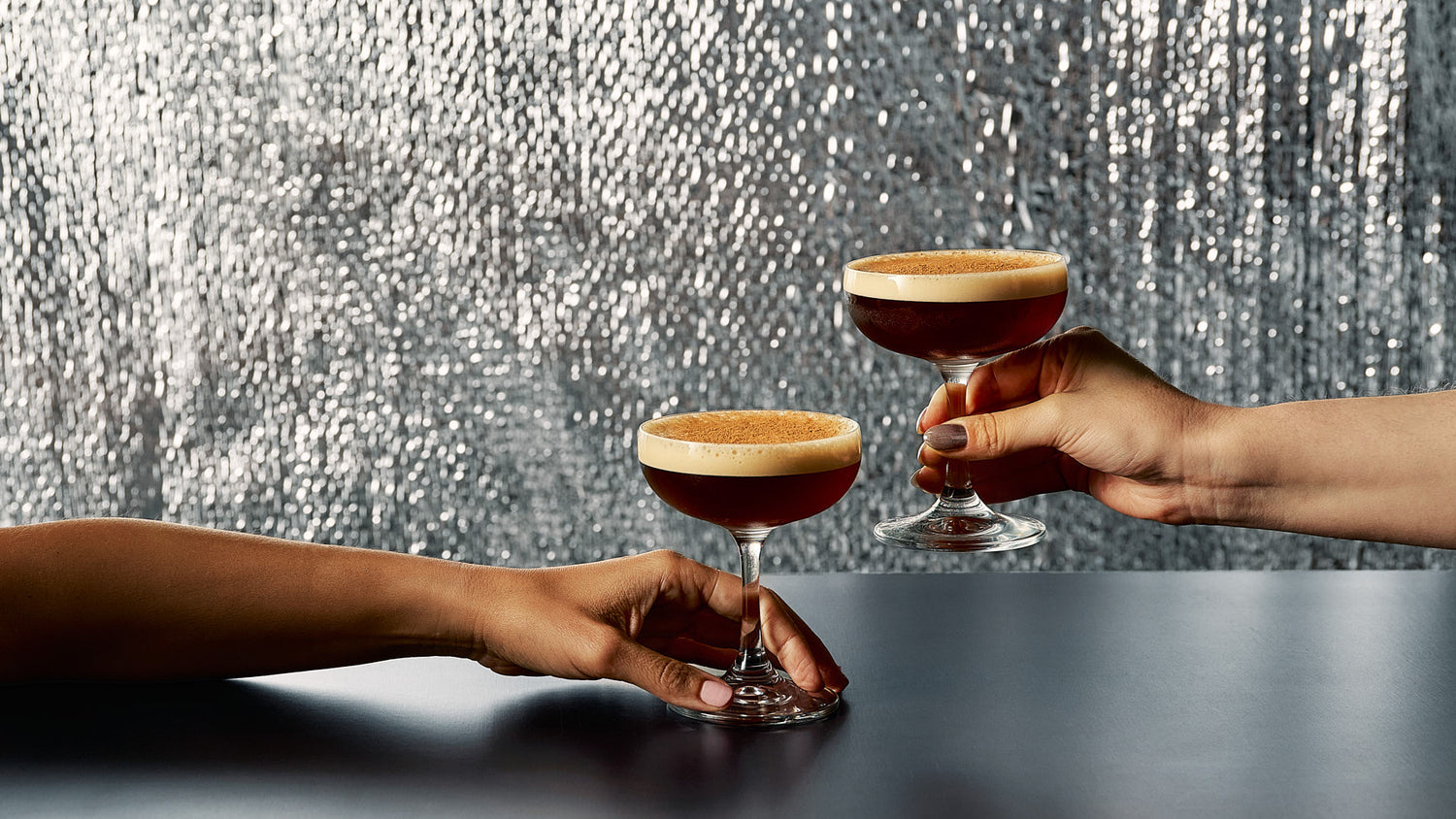 Two people holding espresso gin-tinis, a gin cocktail twist on a the classic espresso martini. Using Four Pillars Gin X Lune Croissanterie Croissant Gin.