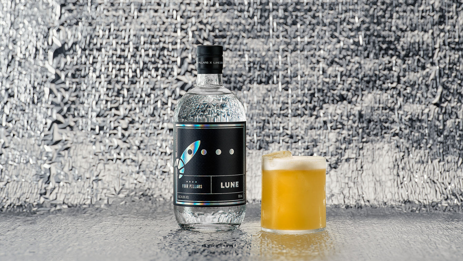 A bottle of Four Pillars Gin and LUNE croissanterie collaboration Croissant Gin next to a sour gin cocktail. 