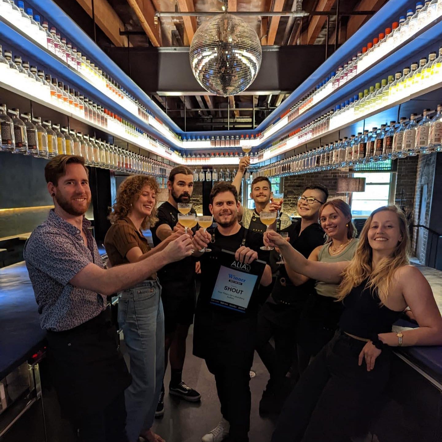 The Four Pillars Lab bar team celebrating an award with drinks, standing in Eileen's Bar.